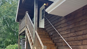 Une cabane en bois avec un escalier en bois menant à une terrasse.