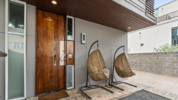Uma entrada moderna com porta de madeira, porta de vidro e duas cadeiras suspensas.