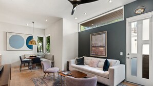 Uma sala de estar moderna com um sofá, cadeiras, uma mesa de centro e obras de arte nas paredes.