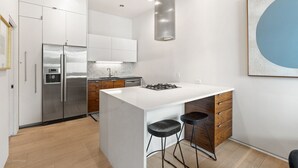 Cozinha moderna com ilha central, eletrodomésticos de aço inoxidável e design minimalista.