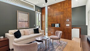 Uma sala de estar moderna com sofá, poltronas, mesa de centro e um painel de parede em madeira.