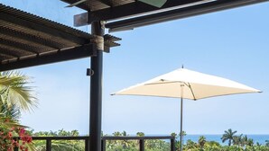 A poolside area with a covered seating area, a table with drinks, and a view of the ocean. - Condo Piscis in Las Marietas by Mita Residential. Golf Cart, Cook, Ocean View, Pool (Punta Mita)