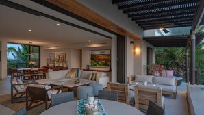 A spacious living area with a large round table, comfortable seating, and a view of the outdoors. - Condo Piscis in Las Marietas by Mita Residential. Golf Cart, Cook, Ocean View, Pool (Punta Mita)