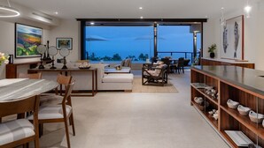 A modern living room with a dining area, large windows, and a view of the ocean. - Condo Piscis in Las Marietas by Mita Residential. Golf Cart, Cook, Ocean View, Pool (Punta Mita)