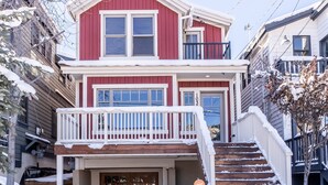 Ein zweistöckiges Haus mit roter Fassade, einer Veranda und einer Treppe, die zum Eingang führt.