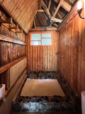 A wooden cabin with a stone-lined floor, a window with frosted glass, and a wooden ceiling. - Tayrona Cachaco River  (Santa Marta)