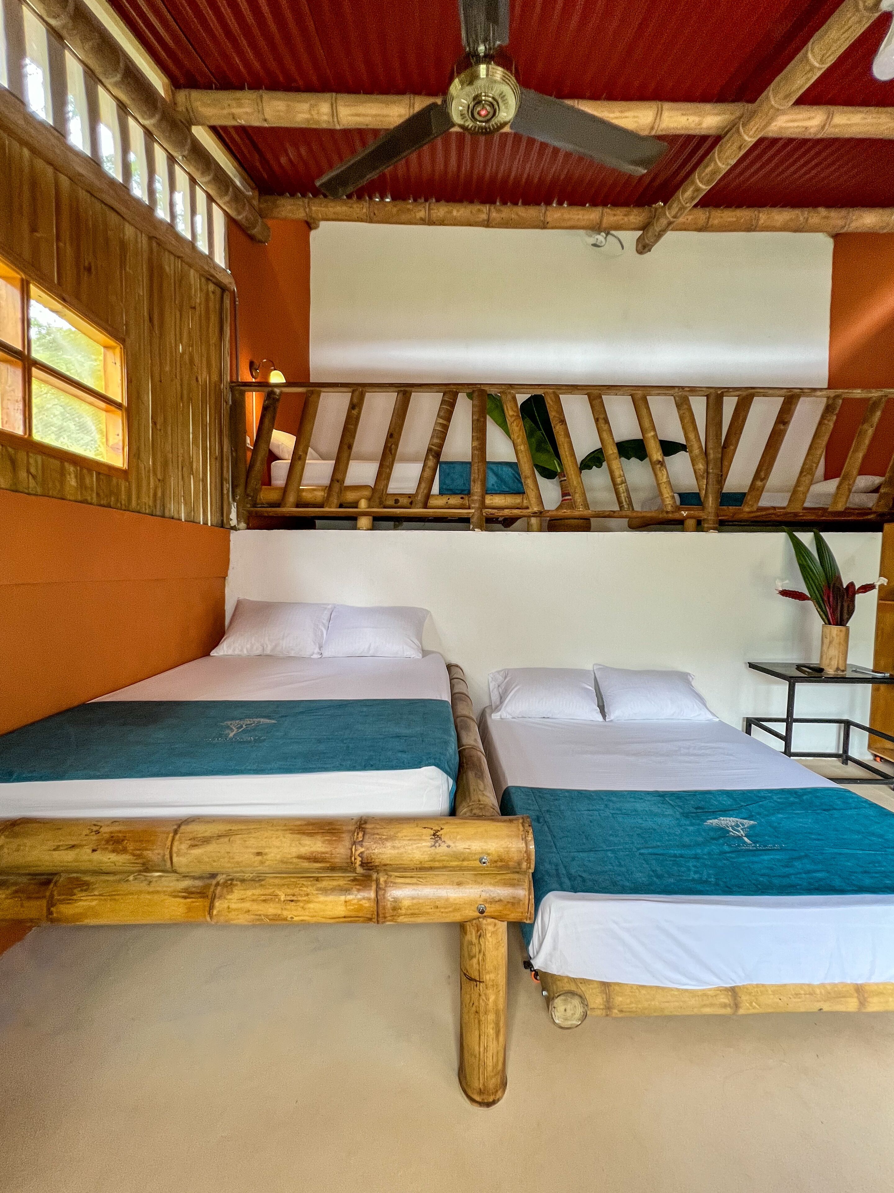 A room with two beds, a ceiling fan, and a window.