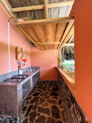 A kitchen with a stone floor, a gas stove, and a wooden ceiling. - Tayrona Cachaco River  (Santa Marta)