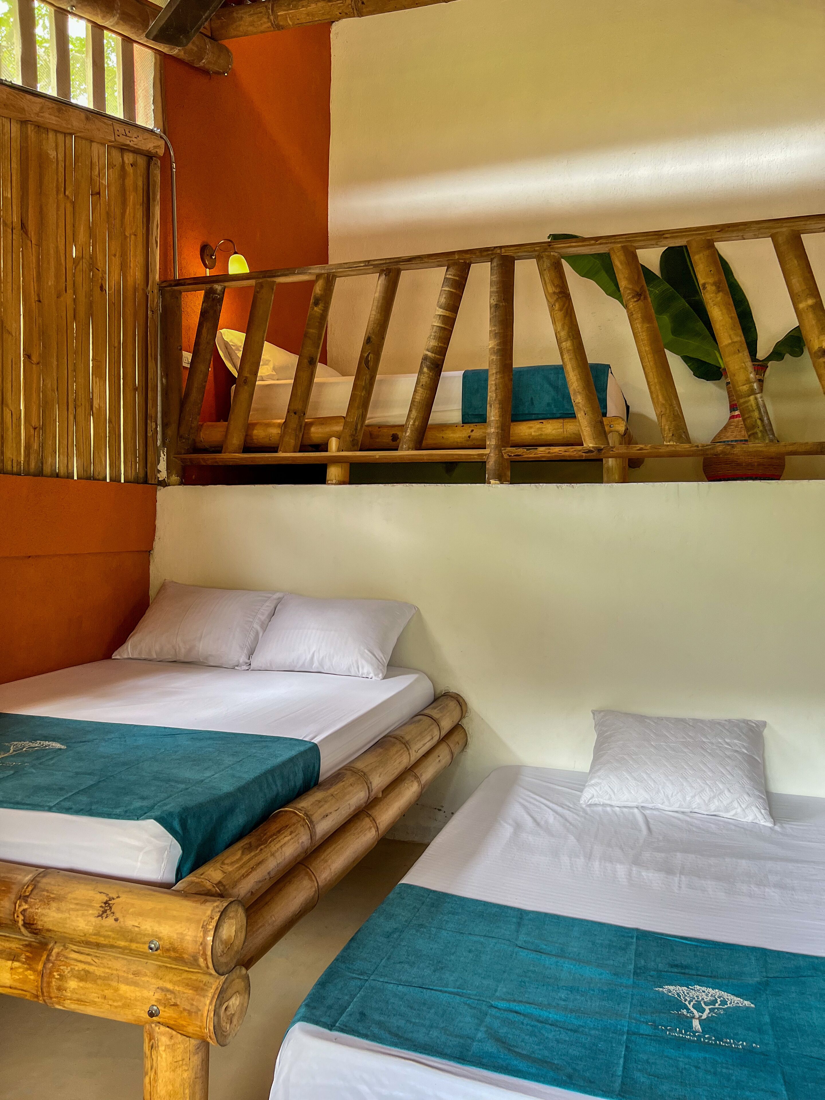 A room with two beds, one with a wooden headboard and the other with a plain headboard.