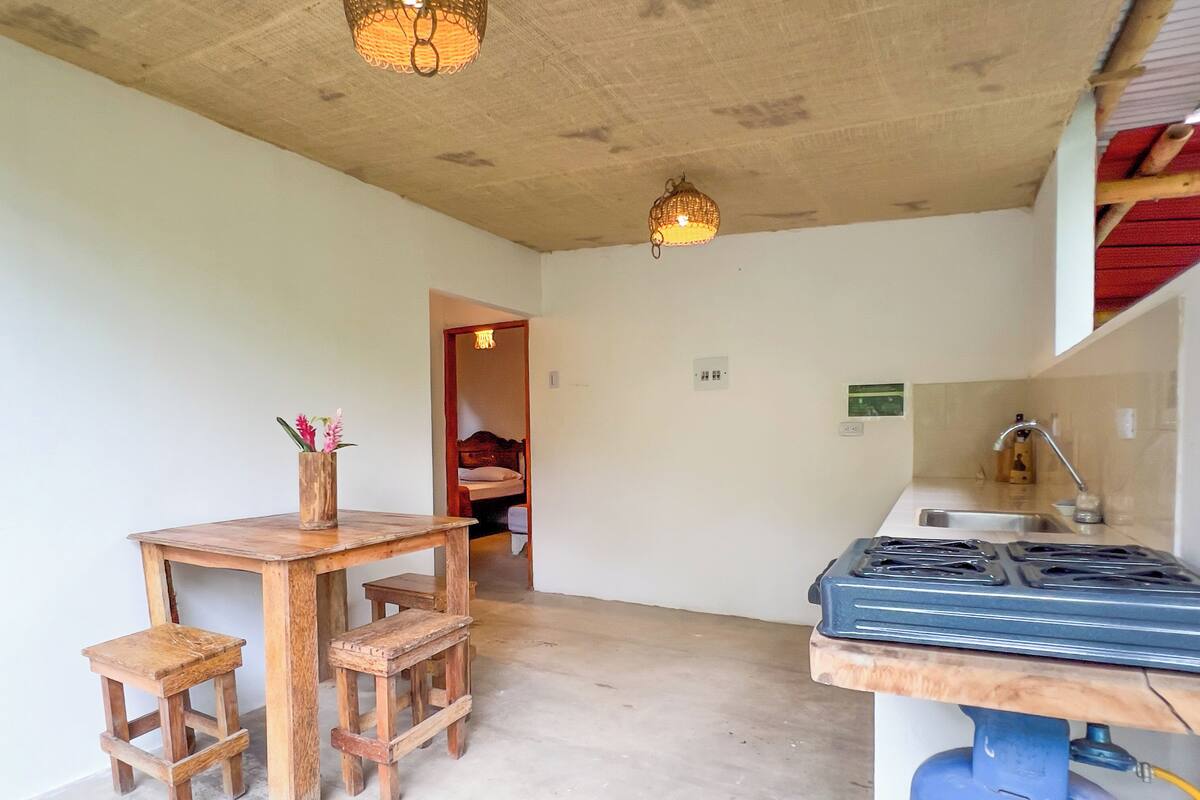 A compact kitchen with a gas stove, wooden table, and stools.