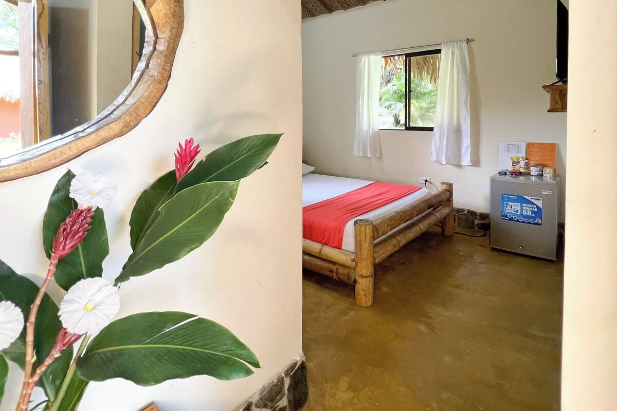 A room with a bed, a mirror, and a small refrigerator.