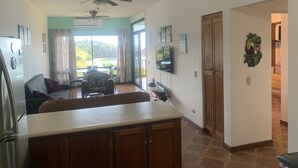 A spacious living area with a view of a beach, a dining area with a table and chairs, and a kitchen with a counter and cabinets. - Beachfront Community Ocean View 2Br/2Ba in Los Almendros, Playa Ocotal (Playa Ocotal)