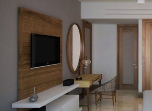 A modern hotel room with a flat-screen TV mounted on a wooden panel, a desk with a chair, a large mirror, and a door leading to another room. - Vidanta Resort Grand Luxxe Deluxxe 1 bedroom in Playa del Carmen Mexico (Playa del Carmen)