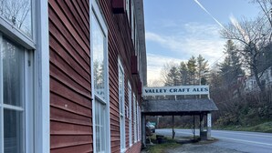 A red building with a sign reading "Valley Craft Ales" and a covered outdoor area. - Valley Craft Ales (Wilmington)