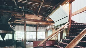 A spacious interior with a large staircase, a central seating area, and exposed wooden beams. - Valley Craft Ales (Wilmington)