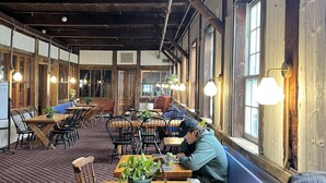 A spacious indoor area with wooden tables and chairs, some with laptops and papers, suggesting a co-working or meeting space. - Valley Craft Ales (Wilmington)