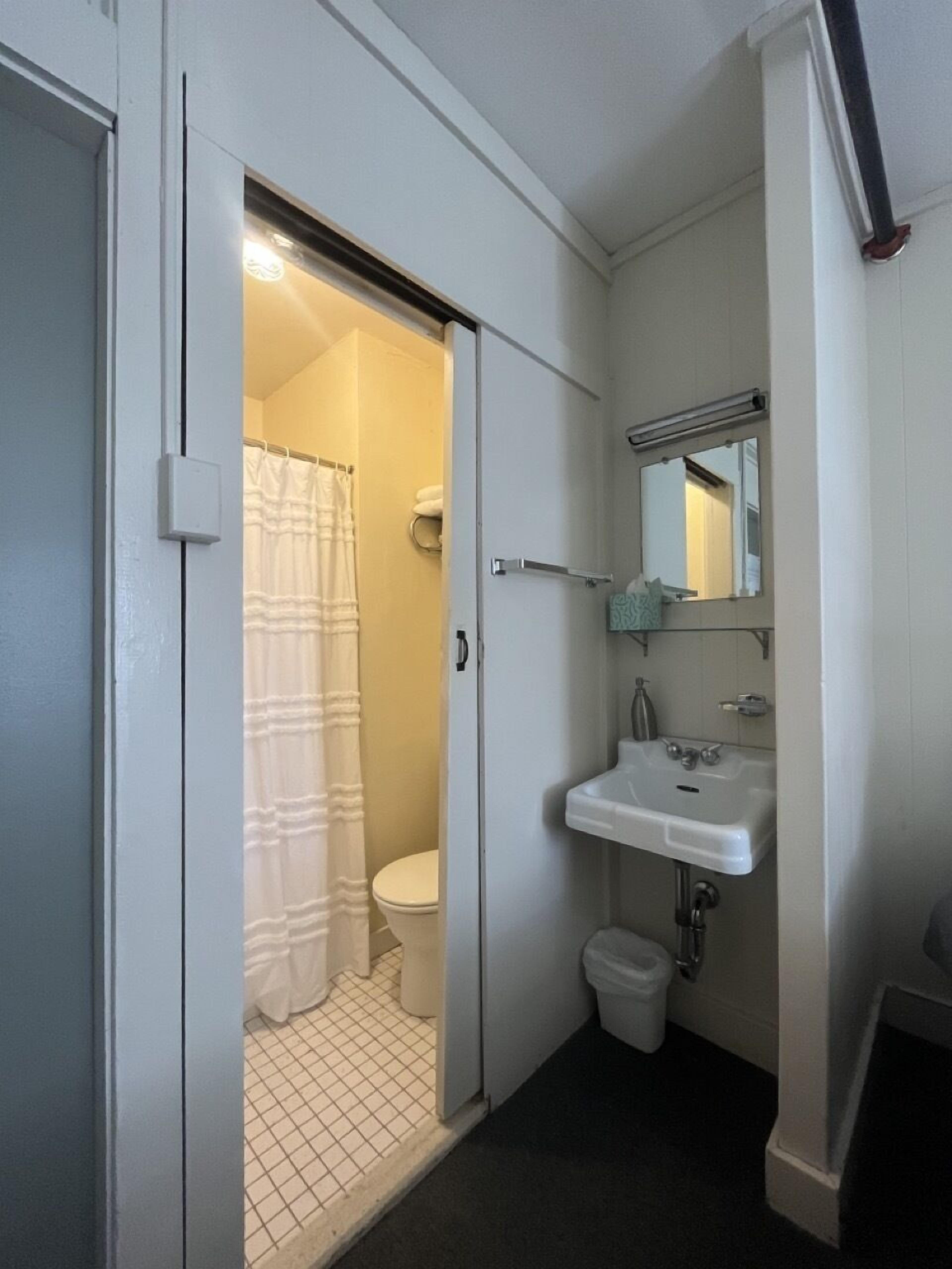 Un baño pequeño con inodoro, lavamanos y cortina de ducha.