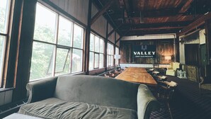 A rustic interior with a long wooden table, a sofa, and a sign reading "VALLEY CRAFT ALES PRESENTS". - Valley Craft Ales (Wilmington)