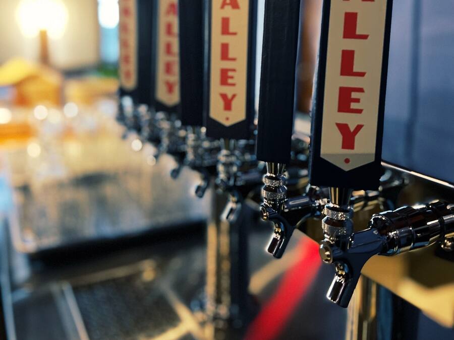 Eine Reihe von Bierhähnen mit der Aufschrift „VALLEY“ und dem Logo roter Bäume.