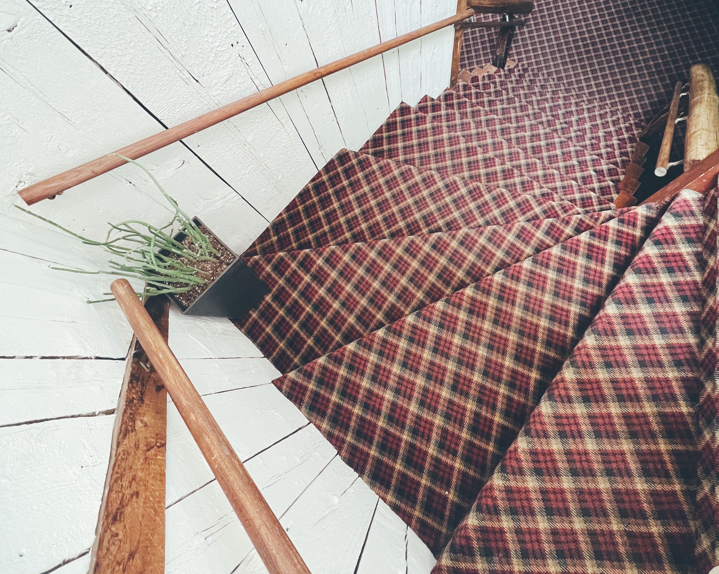 A wooden floor with a checkered fabric sofa and a small potted plant.