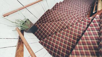 A wooden floor with a checkered fabric sofa and a small potted plant.