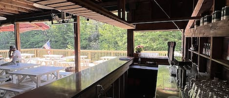 A bar area with wooden beams, a counter, and a view of the outdoors.