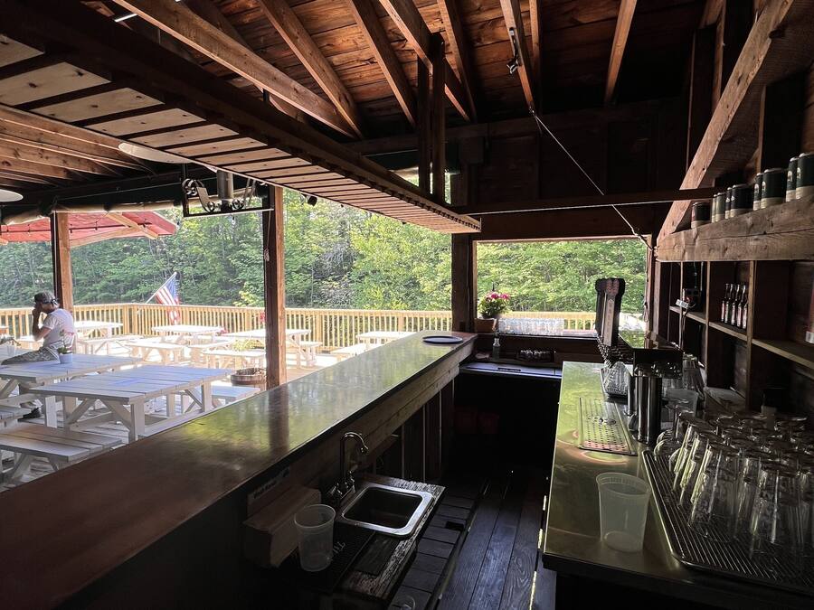 A bar area with wooden beams, a counter, and a view of the outdoors.
