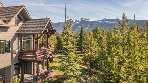 Eine Hütte mit einem Balkon, der auf einen Wald und Berge blickt.