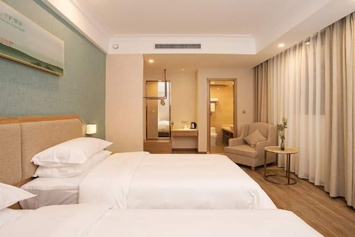 A hotel room with a large bed, a small table, a chair, and a bathroom visible through an open door.