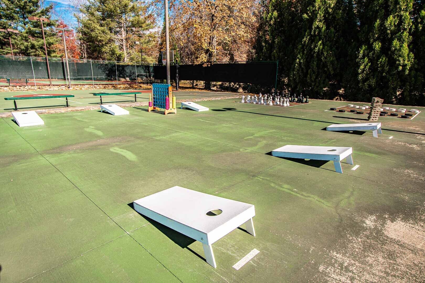 An outdoor recreational area with green artificial turf, white benches, and a chessboard.