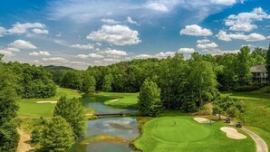 Golfkenttä, jossa on lampi, puita ja taustalla näkyvä rakennus.