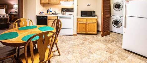 A compact kitchen with wooden cabinets, a microwave, a stove, and a washing machine.