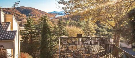 A deck with outdoor seating overlooking a forested valley and mountains.