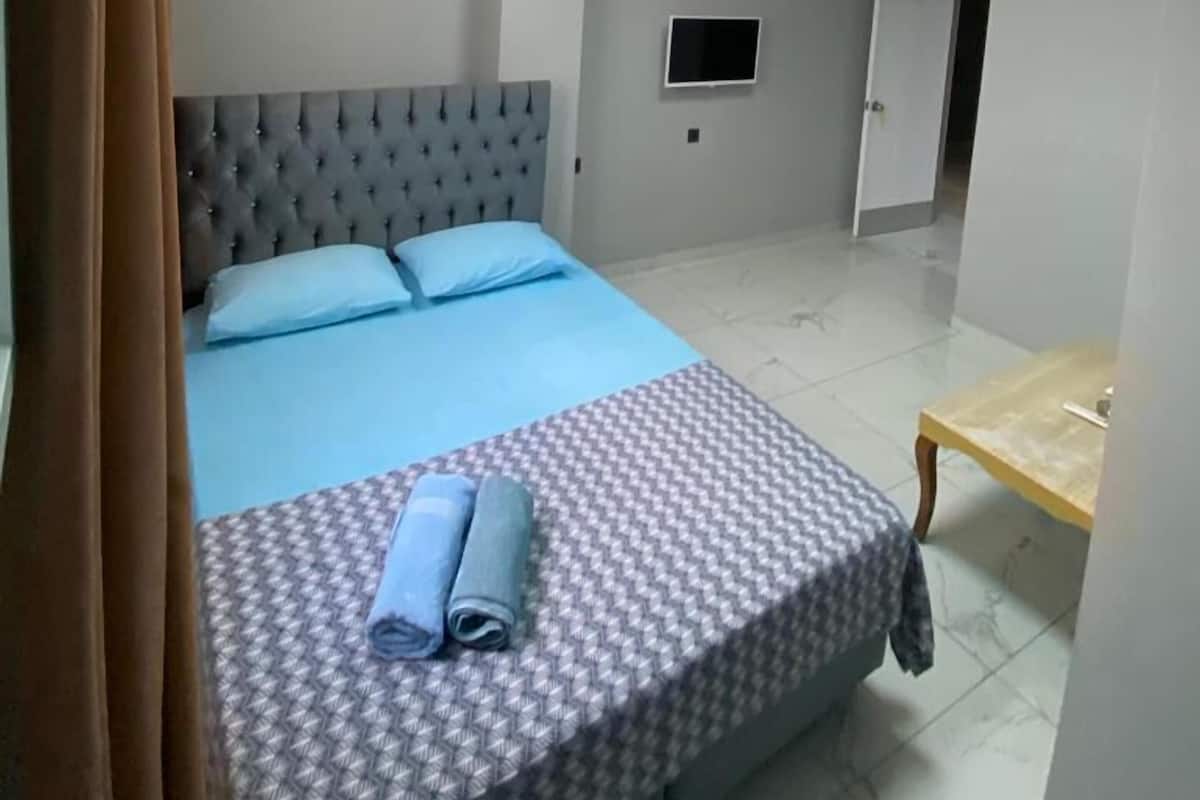 Et soveværelse med en seng, et fladskærms-tv, en aircondition og et loft med et mønstret design.
