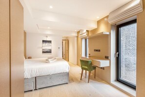 A modern bedroom with a bed, a desk, and a large window.