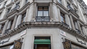 Un bâtiment d’angle doté d’une entrée imposante, de panneaux indiquant « Tory Burch » et « Regent Street W1 », et d’un auvent vert.
