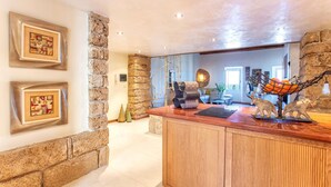 A lobby with a stone wall, a wooden reception desk, and framed artwork on the wall. - Cavour Loft in Alghero (Alghero)