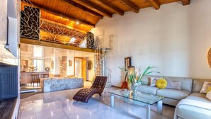 A spacious living room with a high ceiling, a glass coffee table, a leather armchair, and a sofa. - Cavour Loft in Alghero (Alghero)
