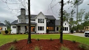 A two-story house with a stone facade, large windows, and a well-maintained lawn. - Golf Rental! House in Champions Retreat (Evans)