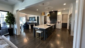 A spacious kitchen with a central island, dark wood flooring, and modern appliances. - Golf Rental! House in Champions Retreat (Evans)