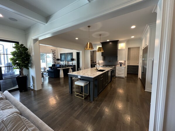 A spacious kitchen with a central island, dark wood flooring, and modern appliances.