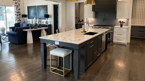 A modern kitchen with a marble island, pendant lighting, and dark cabinetry. - Golf Rental! House in Champions Retreat (Evans)