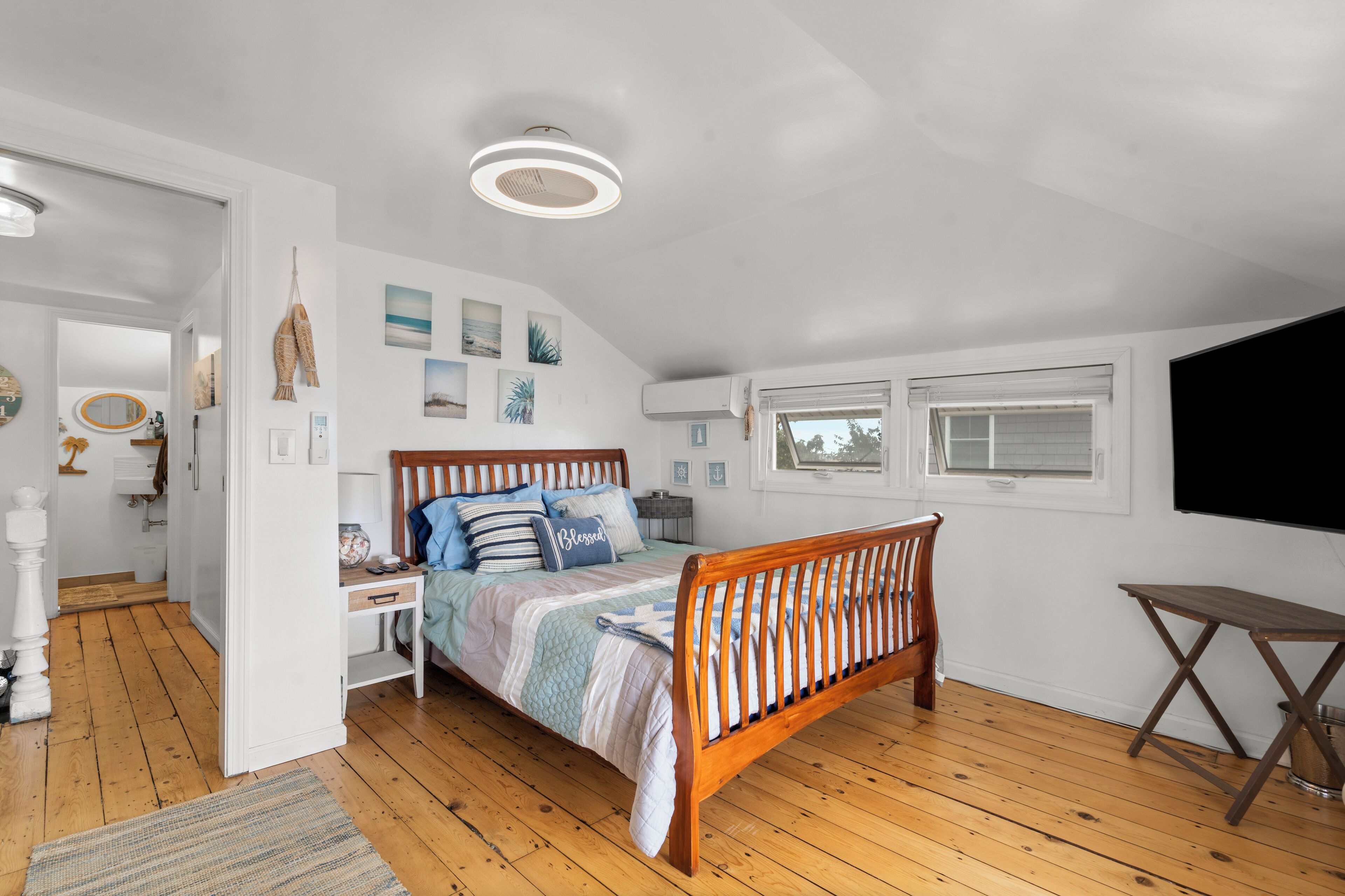A bedroom with a wooden bed, white walls, and a ceiling light.