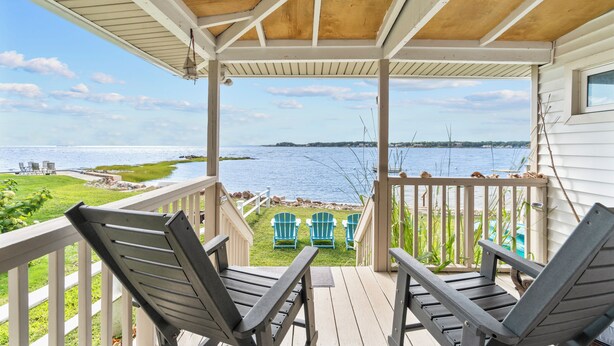 A covered porch with two Adirondack chairs facing a view of a lake and shoreline. - The Dream Location for Your Perfect Vacation  (Branford)