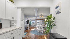 A modern kitchen with white cabinetry, a coffee maker, and a dining area with a round table and chairs. - The Dream Location for Your Perfect Vacation  (Branford)
