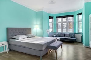 A bedroom with a bed, bedside table, lamp, and a window with a view.