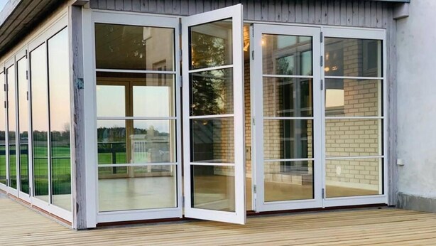 A modern building with a wooden deck and large glass sliding doors. - Captivating 4-bed Villa in Idestrup (Idestrup)