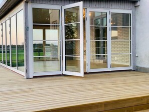 A modern building with a wooden deck and large glass sliding doors. - Captivating 4-bed Villa in Idestrup (Idestrup)