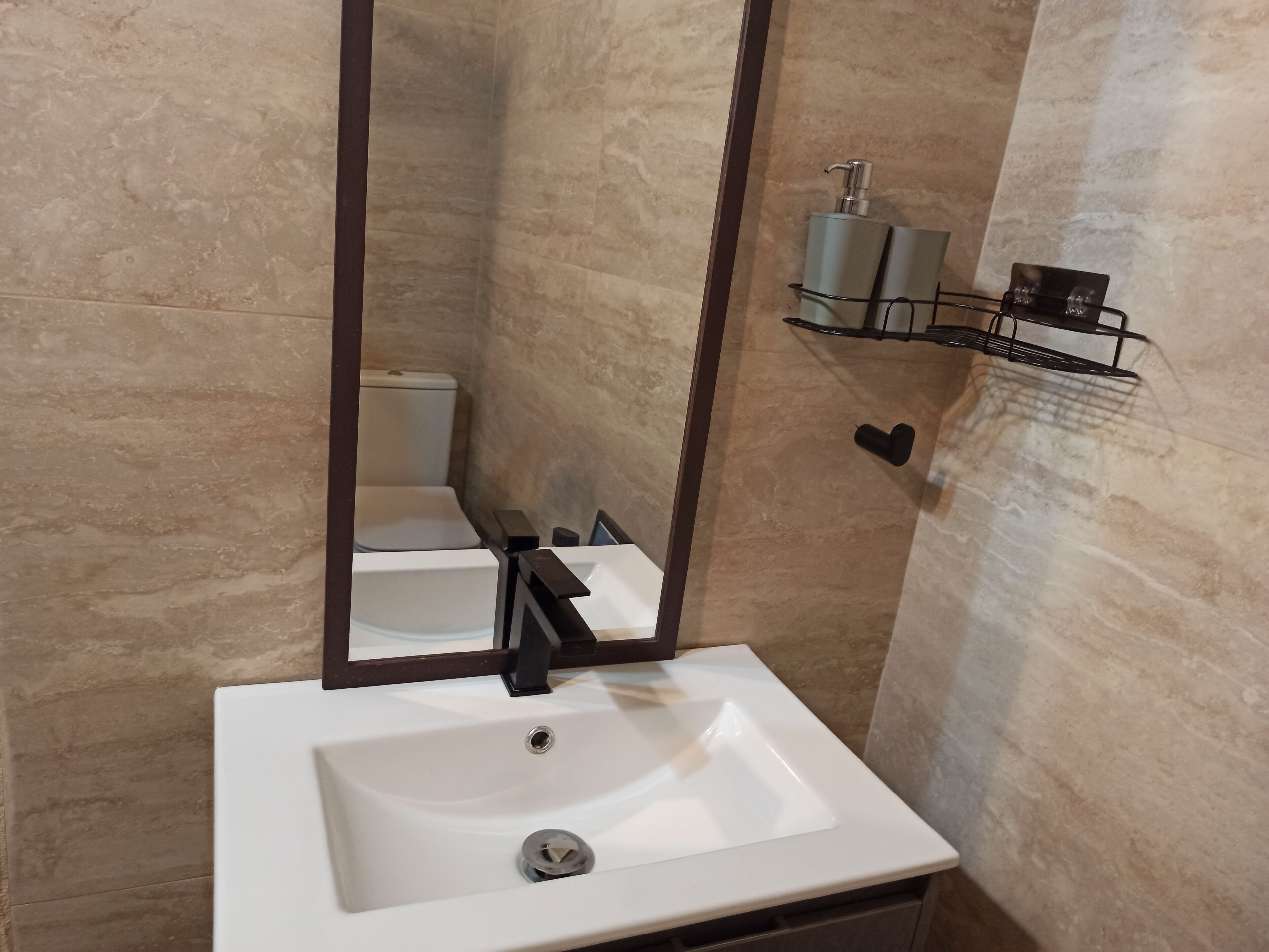 Un baño con lavamanos blanco, un espejo y un inodoro.