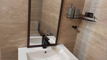 Un baño con lavamanos blanco, un espejo y un inodoro.